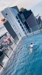 芭堤雅市中心BASE Central PATTAYA Long Balcony with Infinity Pool & Free Netflix!的建筑物前水塘里的人