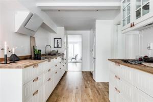 KullavikKullavik, 2 mil från Göteborg Villa Gläntan的厨房铺有木地板,配有白色橱柜。