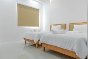 董里S1 Trang Hotel的两张带白色床单的床和客房内的窗户