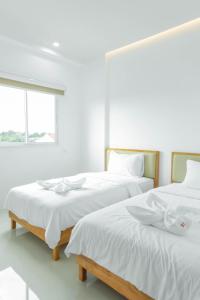 董里S1 Trang Hotel的白色客房的两张床,设有窗户