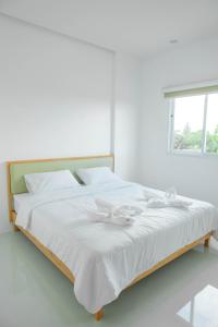 董里S1 Trang Hotel的一张白色的床,上面有两只白色的弓