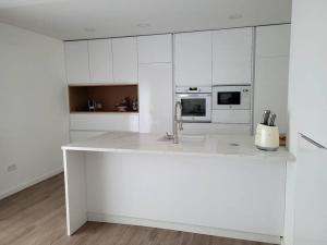 吉马良斯Cidade_Berço House的厨房配有白色橱柜和白色台面