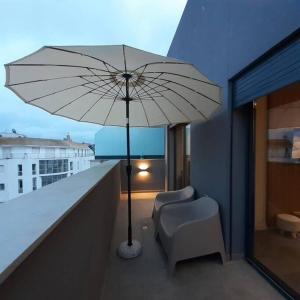 卡萨布兰卡Cosy Appartement Au Centre de Casablanca的阳台上的白色遮阳伞和椅子