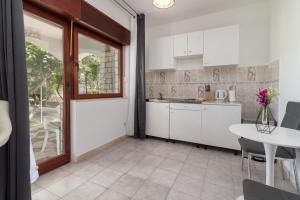 特罗吉尔Apartments Bozan的厨房配有白色橱柜和桌子