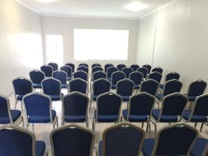 Berea HillsConmilla Guest House and Conference Venue的一间空房间,配有蓝色椅子和投影屏幕