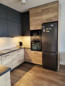 比得哥什Apartament w Parku nad Kanałem的厨房配有黑色冰箱和木制橱柜。