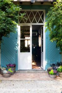 卡斯泰BEL AIR MAISON D'HOTES DES LANDES的蓝色的房子,有白色的门和一些植物