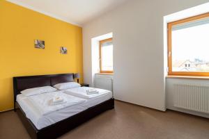 HoražďoviceHotel Prácheň的一间卧室设有一张黄色墙壁的床和两个窗户