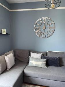 克里克豪厄尔Cosy 2 bed flat in Crickhowell的客厅配有一张沙发,墙上挂着一个钟