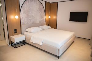 卡萨米尔Colosseum Hotel的卧室配有白色的床和平面电视。
