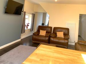 曼彻斯特Greenwood的客厅配有2张棕色皮沙发和1张桌子