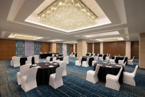 阿格拉Fairfield by Marriott Agra的一间会议室,配有桌椅和吊灯