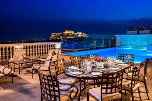 雅典King George, a Luxury Collection Hotel, Athens的夜间阳台上的桌椅