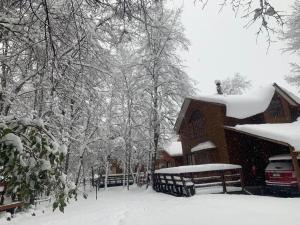 拉斯特朗卡斯Cabañas Bordenieve的一座雪覆盖的房子,前面有一辆汽车停放