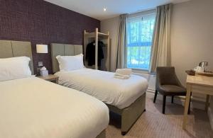 史云顿Lydiard Park Hotel & Conference Centre的酒店客房配有两张床和一张书桌