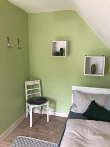 黑林山区舍瑙GartenFerienhaus "AnnaLuise"的卧室拥有绿色的墙壁,配有椅子和床