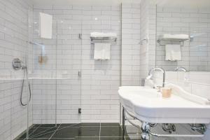 霍森斯Jørgensens Hotel的白色的浴室设有水槽和淋浴。