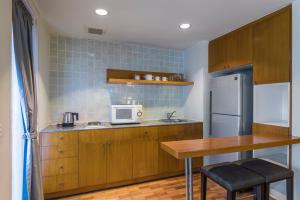 曼谷察殿曼谷沙屯酒店式公寓的厨房配有桌子、微波炉和冰箱。