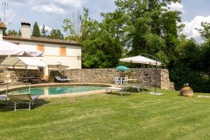 蒙特里久尼Casale Mulin Bianco的庭院内的游泳池,配有椅子和遮阳伞
