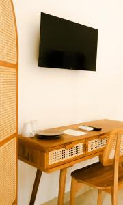 坎古Shortcut Breeze Guest House的木桌,墙上有电视