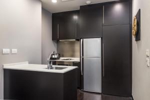 曼谷察殿曼谷河畔酒店的厨房配有黑色橱柜和不锈钢冰箱