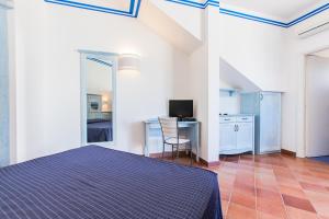 法维尼亚纳Resort Cala La Luna的一间卧室配有一张床和一张书桌及电视