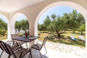 瓦西里科斯Lenna's Villas Zante的庭院配有桌椅和树木
