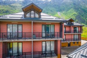 卡兹贝吉Kazbegi MaNa Apartment N 111的一座红砖建筑,设有阳台,享有山脉的背景