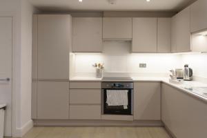 伦敦Gorgeous New 2 Bed Flat - 2 August House的厨房配有白色橱柜和烤箱。