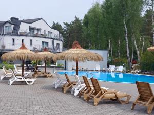 波别罗沃Apartament Bursztyn的一组椅子和遮阳伞,位于游泳池旁