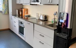 Øvre ÅrdalSitla Hotel & Appartments的厨房配有白色橱柜和黑色冰箱。