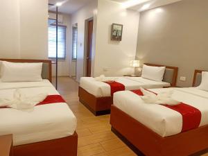 卡尔巴约INNCITY HOTEL的酒店客房带两张红色和白色的床单