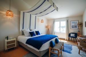 巴尔巴特尔Hôtel Le Noirmoutier的一间卧室配有一张带蓝色床单的床和一扇窗户。