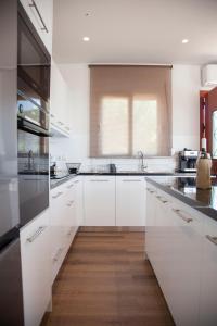 DilinátaVilla Anthodesmi的厨房铺有木地板,配有白色橱柜。