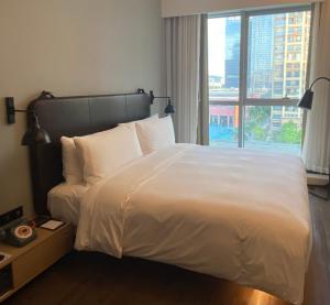 深圳深圳北站Moxy酒店的卧室设有一张大白色的床和大窗户