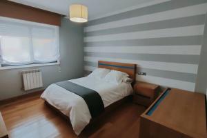 维戈Gran casa pareada con piscina en Vigo. Playa: 9min的一间卧室配有一张带条纹墙的床