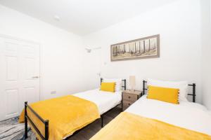 南安普敦Brinton's Road - Modern Studio Apartments in City Centre的配有白色墙壁和黄色床单的客房内的两张床
