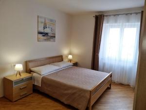 乌马格Apartments Valentina的一间卧室配有一张带两盏灯的床和一扇窗户。