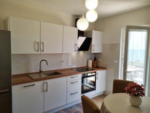 乌马格Apartments Valentina的厨房配有白色橱柜、水槽和桌子