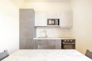 普拉托Appartamento Michelangelo的厨房配有白色橱柜、桌子和微波炉
