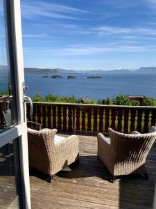 OsøyroBjørnafjorden Hotell的两把柳条椅坐在甲板上,眺望着大海
