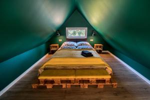 普热谢卡Domandi mountain holiday lodges的一间位于绿色客房内的卧室,配有一张大床