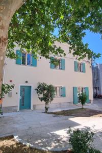 伊佐拉Dea Del Mar Apartments的白色的建筑,有蓝色的门和树