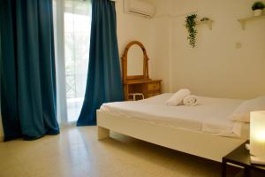 梅内乌Yiallos Village Apt. A101的一间卧室配有一张带蓝色窗帘的床和一扇窗户