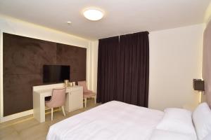 比森齐奥营M2 Hotel的酒店客房配有一张床、一张书桌和一台电视。