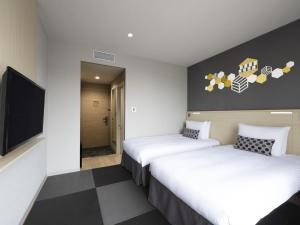 东京宜必思尚品东京东银座酒店的酒店客房设有两张床和一台平面电视。