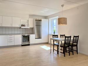 海宁Newly Renovated Two Bedroom Apartment In City Center Of Herning的厨房配有白色橱柜和桌椅