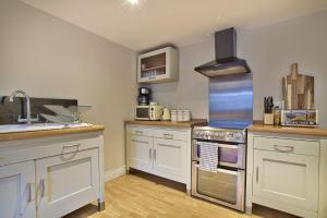 BamptonOlive Cottage by Group Retreats的厨房配有白色橱柜和炉灶烤箱。