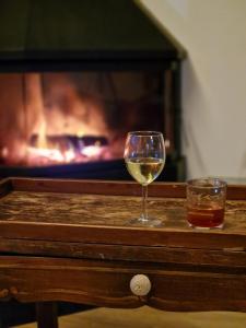 拉维斯瓦尔Turisme Rural Mas Vilà的一杯葡萄酒和一杯威士忌在带壁炉的桌子上