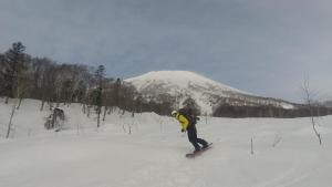 赤井川Ski base的骑着滑雪板沿着雪覆盖的斜坡滑雪的人